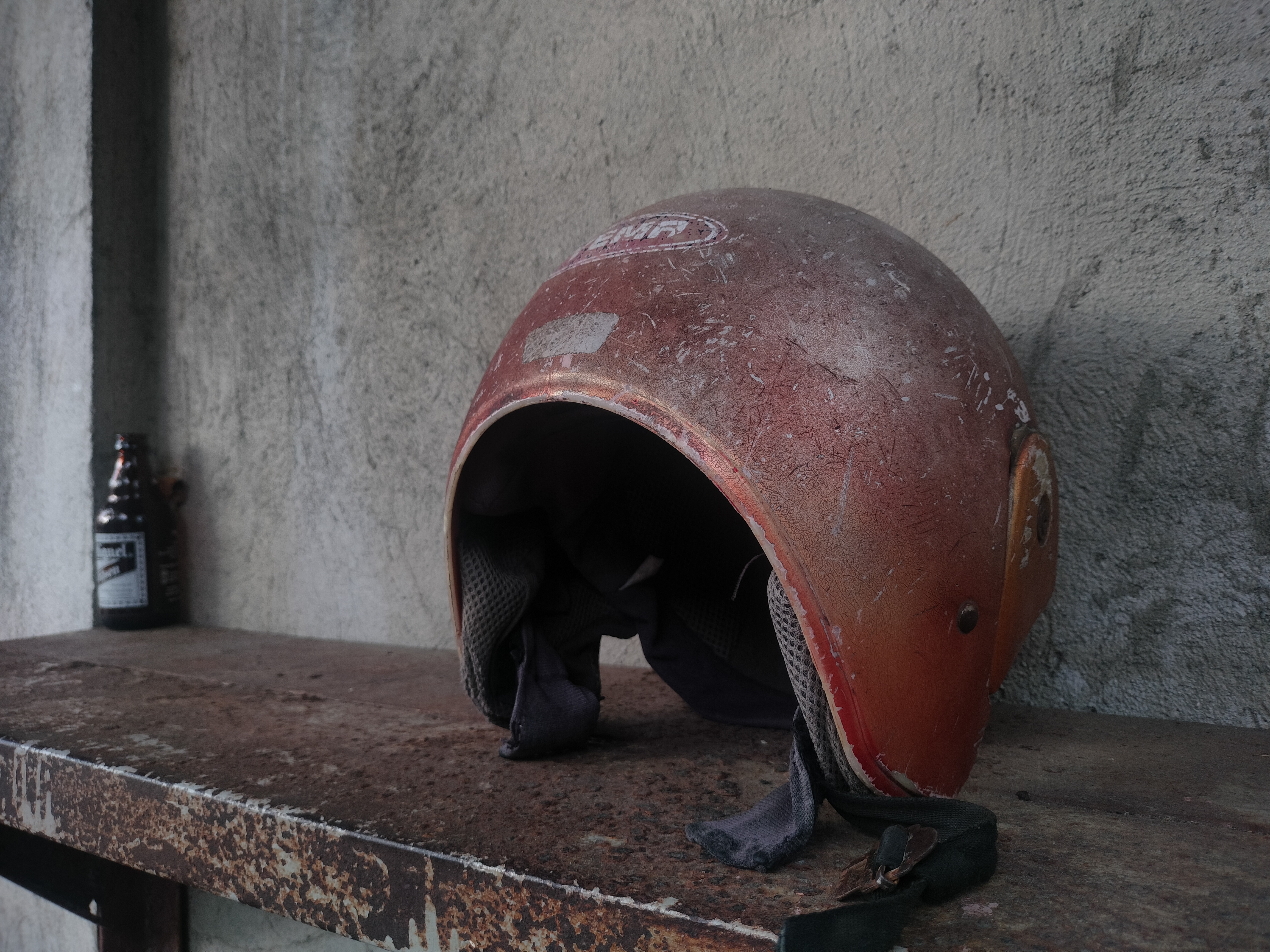 An old helmet next to an empty bottle of beer