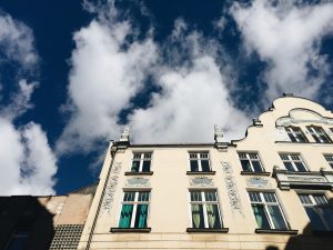 A blue sky with clouds behind the facade of a building decorated in Wrocław, Poland.
