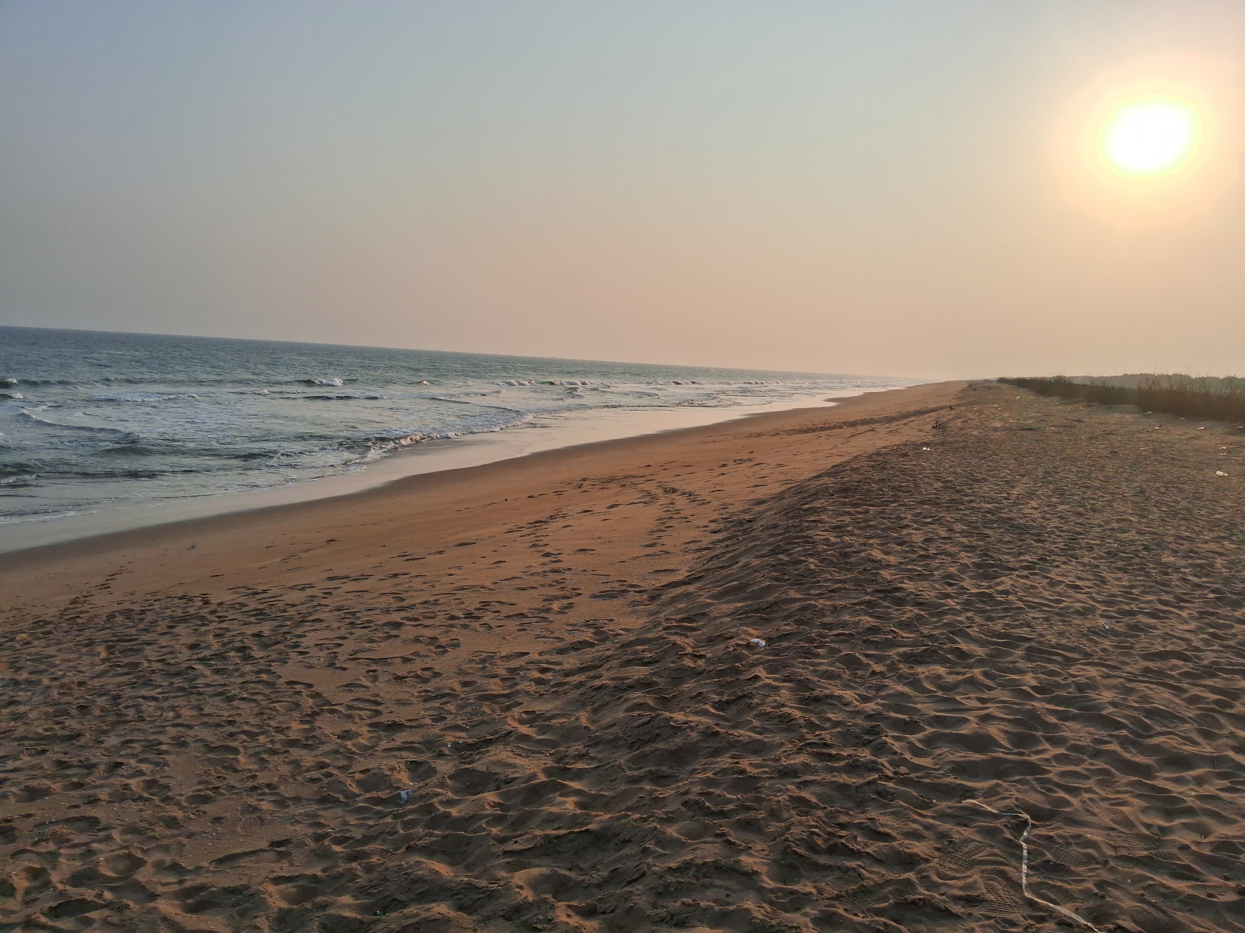 Standing on the beach, the sun is setting in the distance, waves are crashing in.