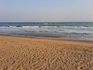 Standing on the beach looking out on the sea. There are big waves.