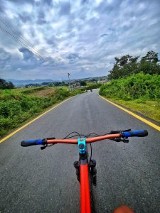 Riding a bicycle without hands on a clear and deserted road.