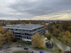 Overcast sky over a modern building beside a river with autumn trees
