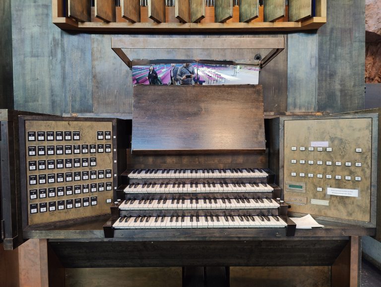 Close-up of an organ’s keyboard at Temppeliaukio Church, Helsinki, with multiple tiers of keys and control panels, reflecting the surrounding area in its polished surface.