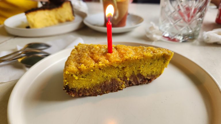 Una porción de pastel con una vela roja encendida