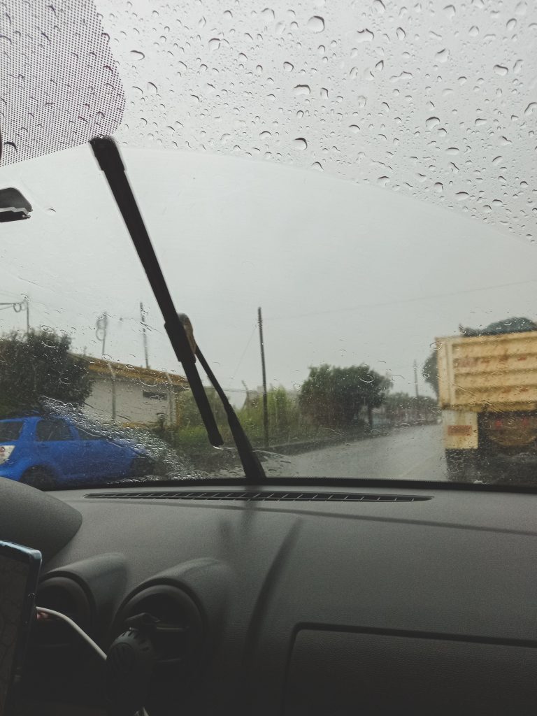 Vista dentro de vehículo afuera fuerte lluvia, vidrio mojado.