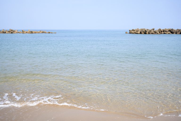 Sea of Japan on a sunny day. The calm water surface creates a tranquil atmosphere, It captures the pristine, sun-drenched coastline.