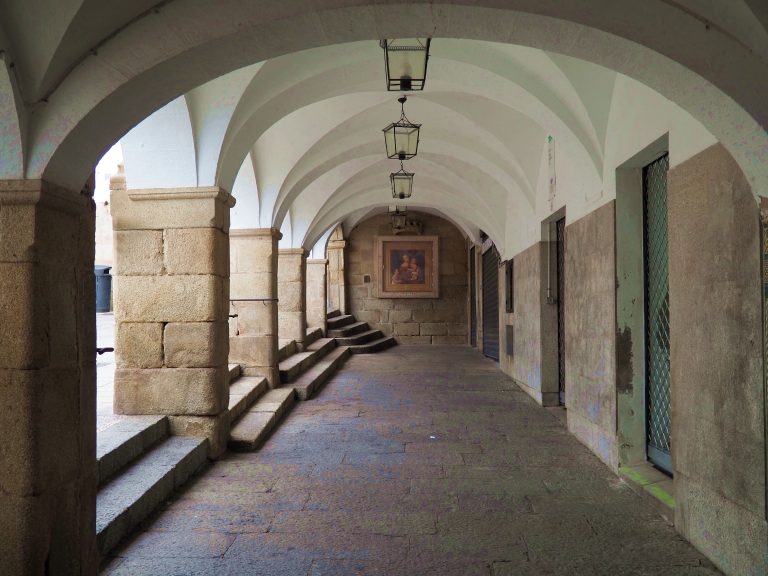 An outdoor archway with a painting on the far end wall.