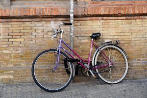 Pink and purple bicycle chained to a traffic sign