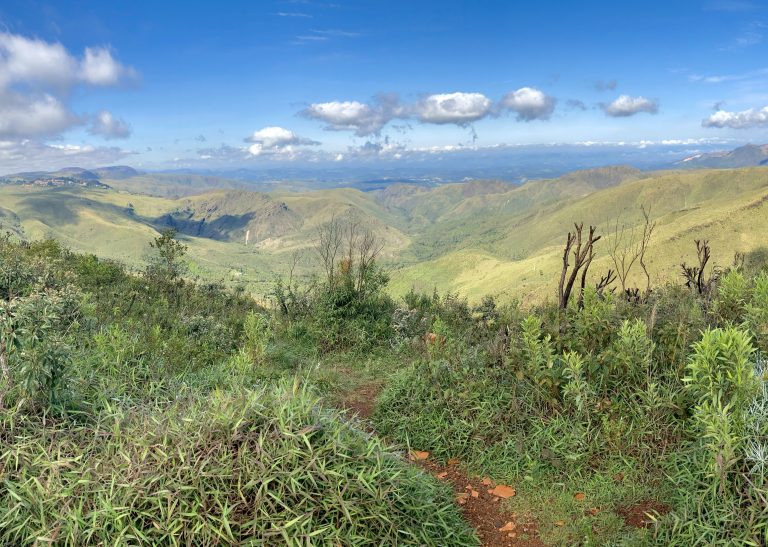 Landscape with some big mountains in the state of Minas Gerais, Brazil. There are also some visible clouds in the sky and some green vegetation by the ground.