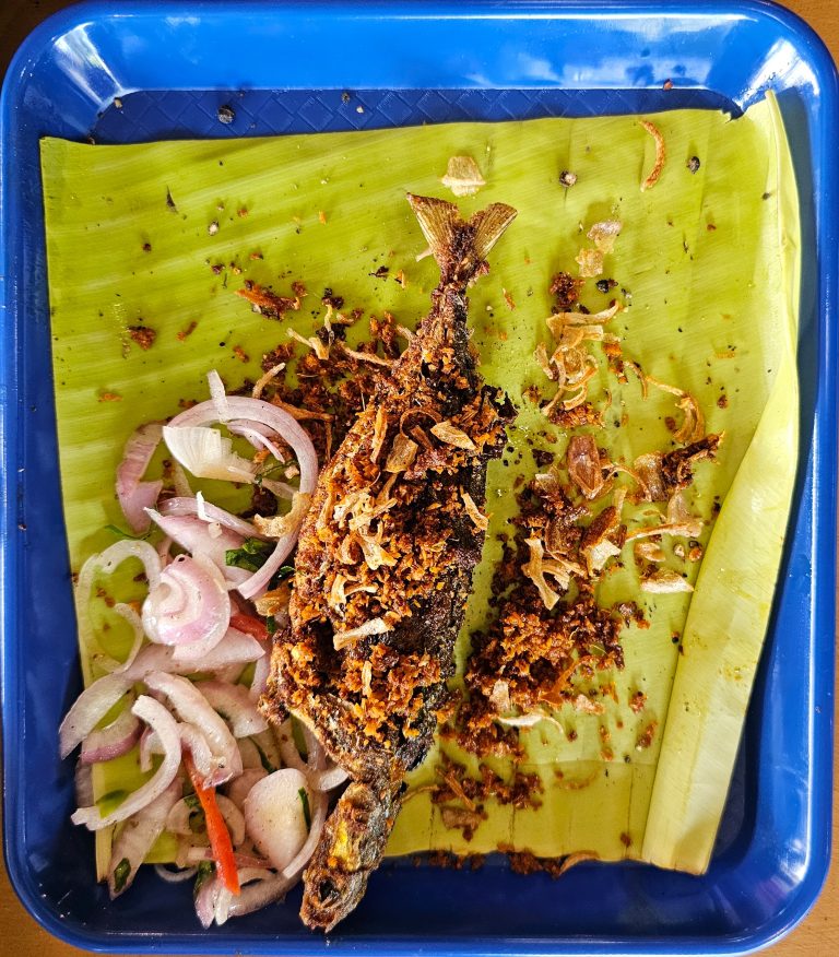 Fried Indian mackerel served on a banana leaf with coconut scrappings.