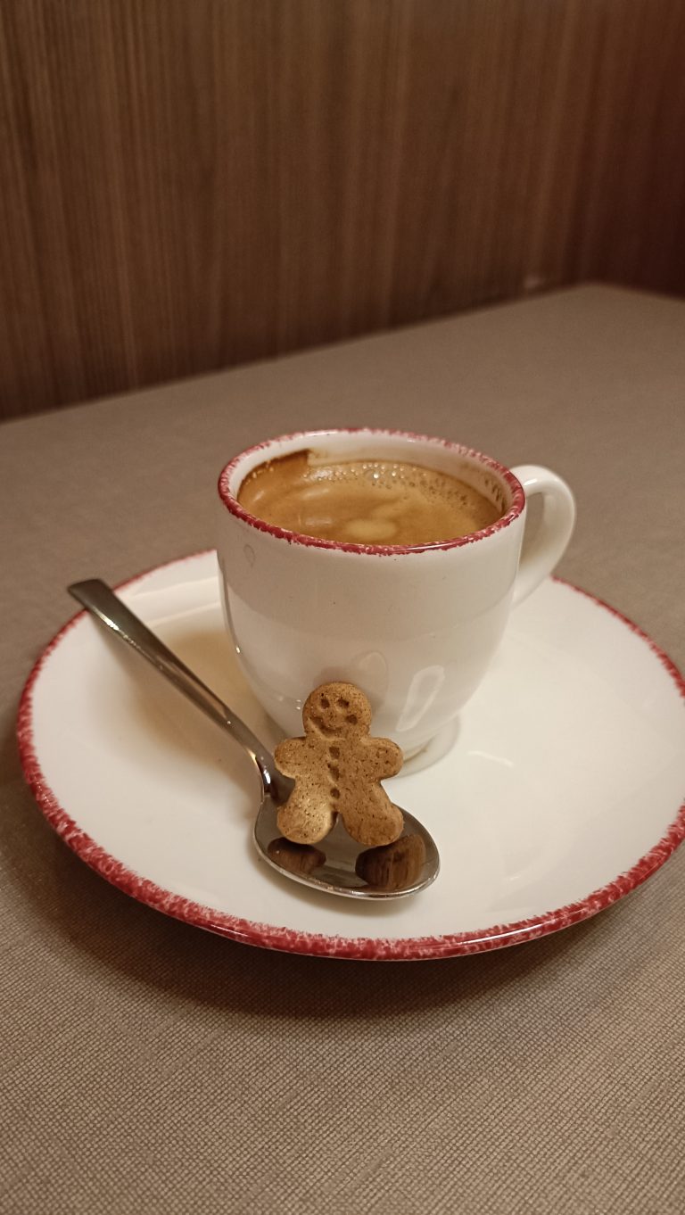 Happy gingerbread man leaning on a coffee cup