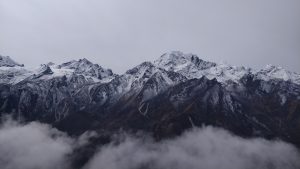 Langtang Trek, standing above the clouds looking at the mountains with a snowy summit
