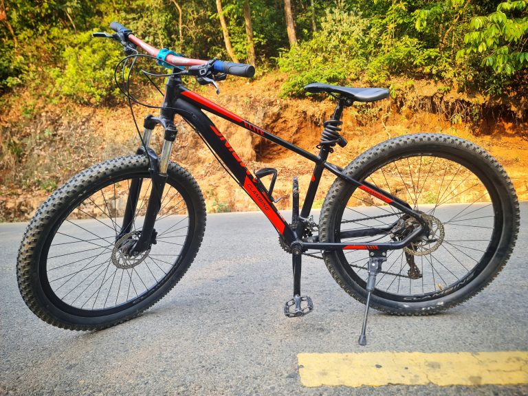 Red mountain bike by the edge of the vacant road.