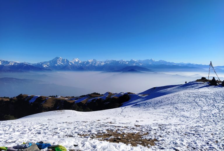 The sky is a brilliant shade of blue, with hills and mountains covered in snow, showcasing the natural beauty of the landscape.