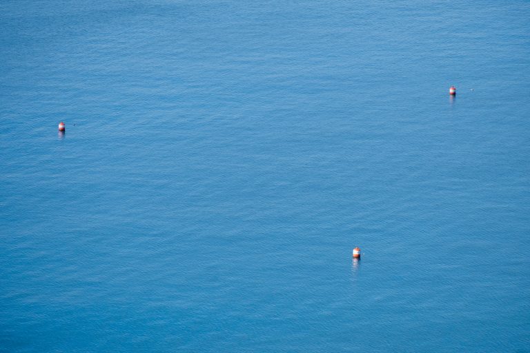 Three white-striped orange buoys in the sea