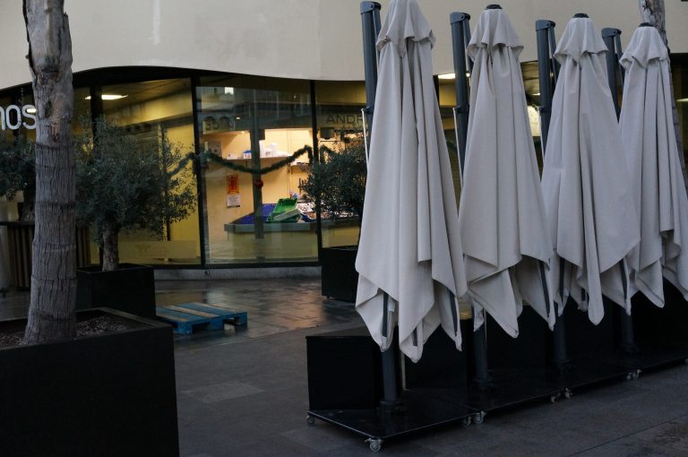 Row of closed umbrellas at a cafe’s terrace