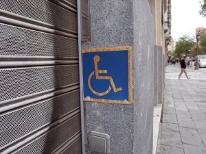 Weathered accesibility sign placed by a store's door