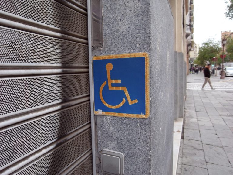 Weathered accesibility sign placed by a store’s door