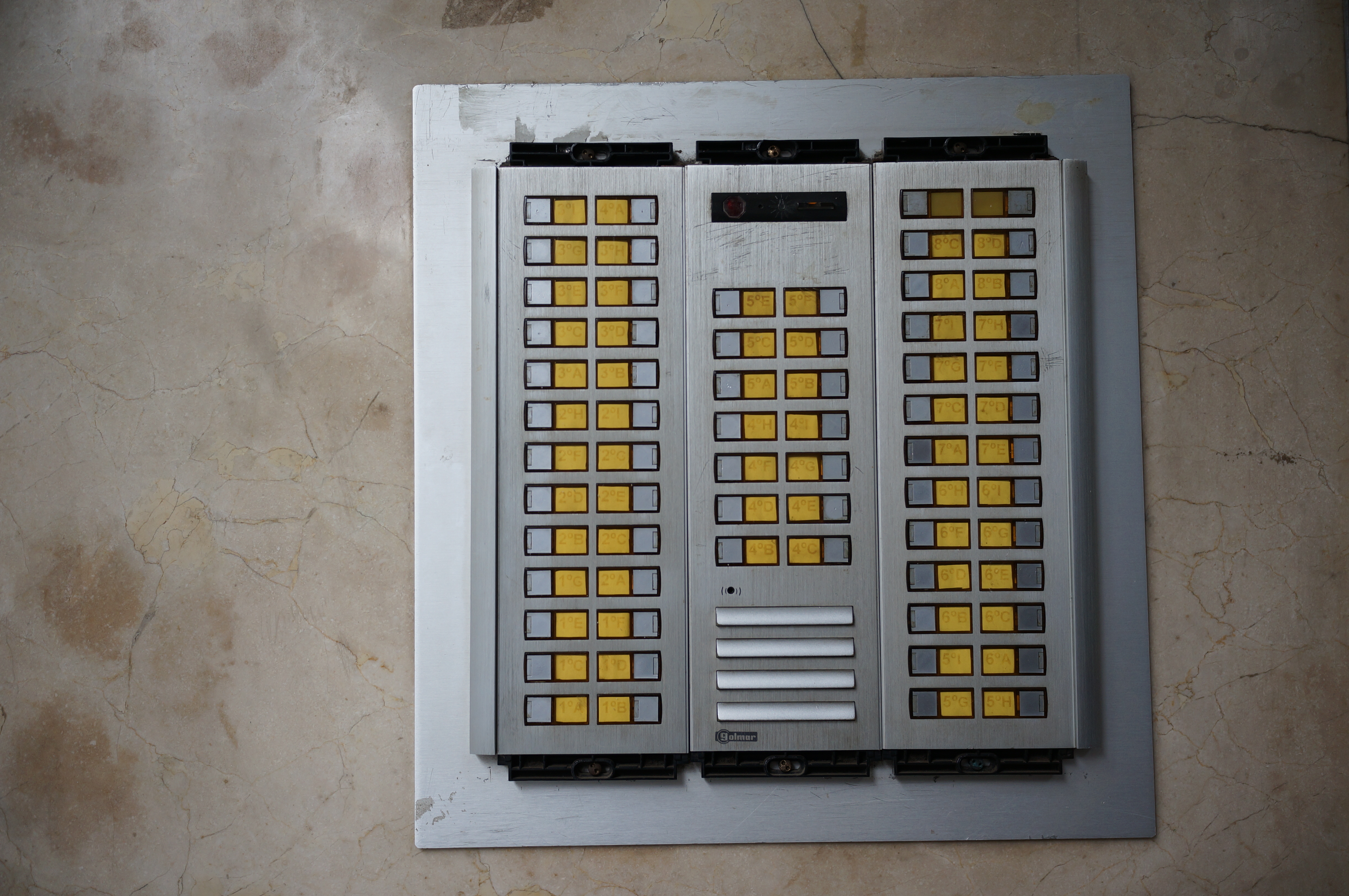 Old and waethered door intercom with many buttons