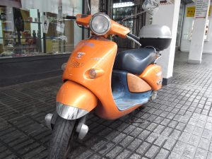 Orange scooter parked on the sidewalk