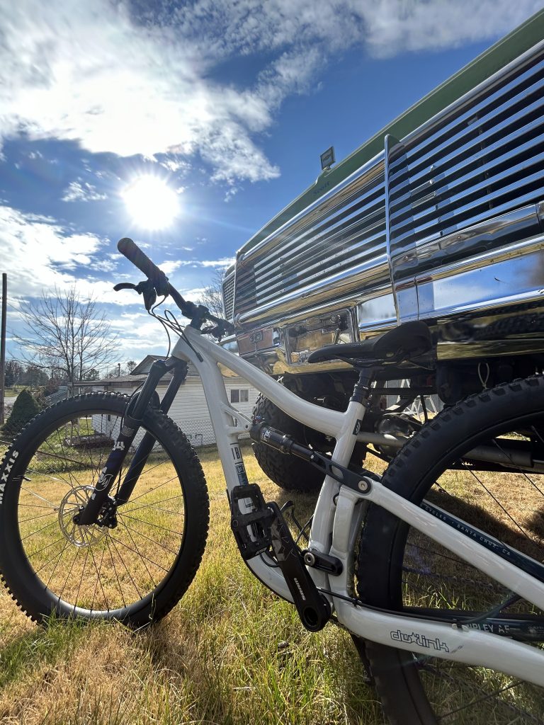 A white mountain bike leaning against the chrome grill of a bright green antique truck