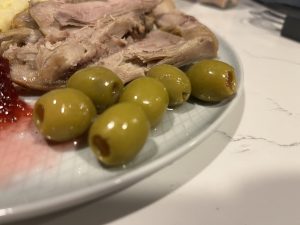 Olives on a plate with turkey and a little cranberry sauce.