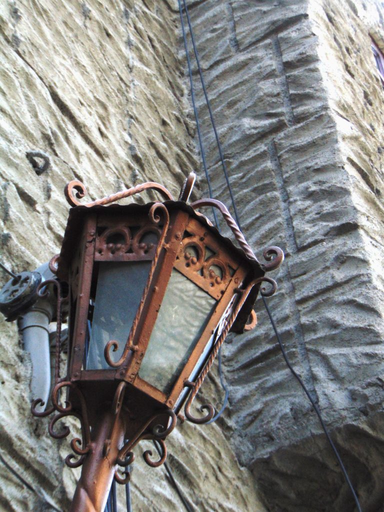 A brown electric lantern (el farol), mounted on a rock wall.