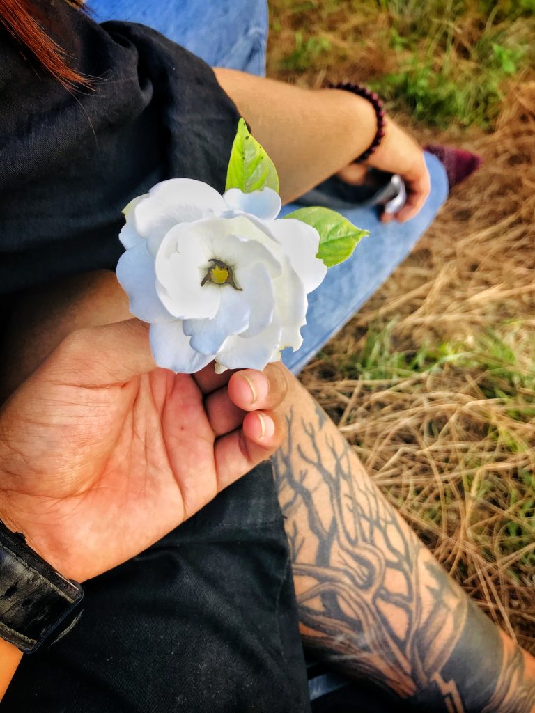 A hand grasping a white blossom.