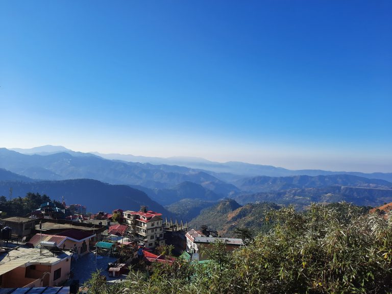 A village surrounded by mountains beneath the vast expanse of the sky within a natural setting.