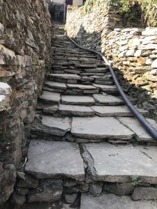 A hose runs up a staircase of flat stone