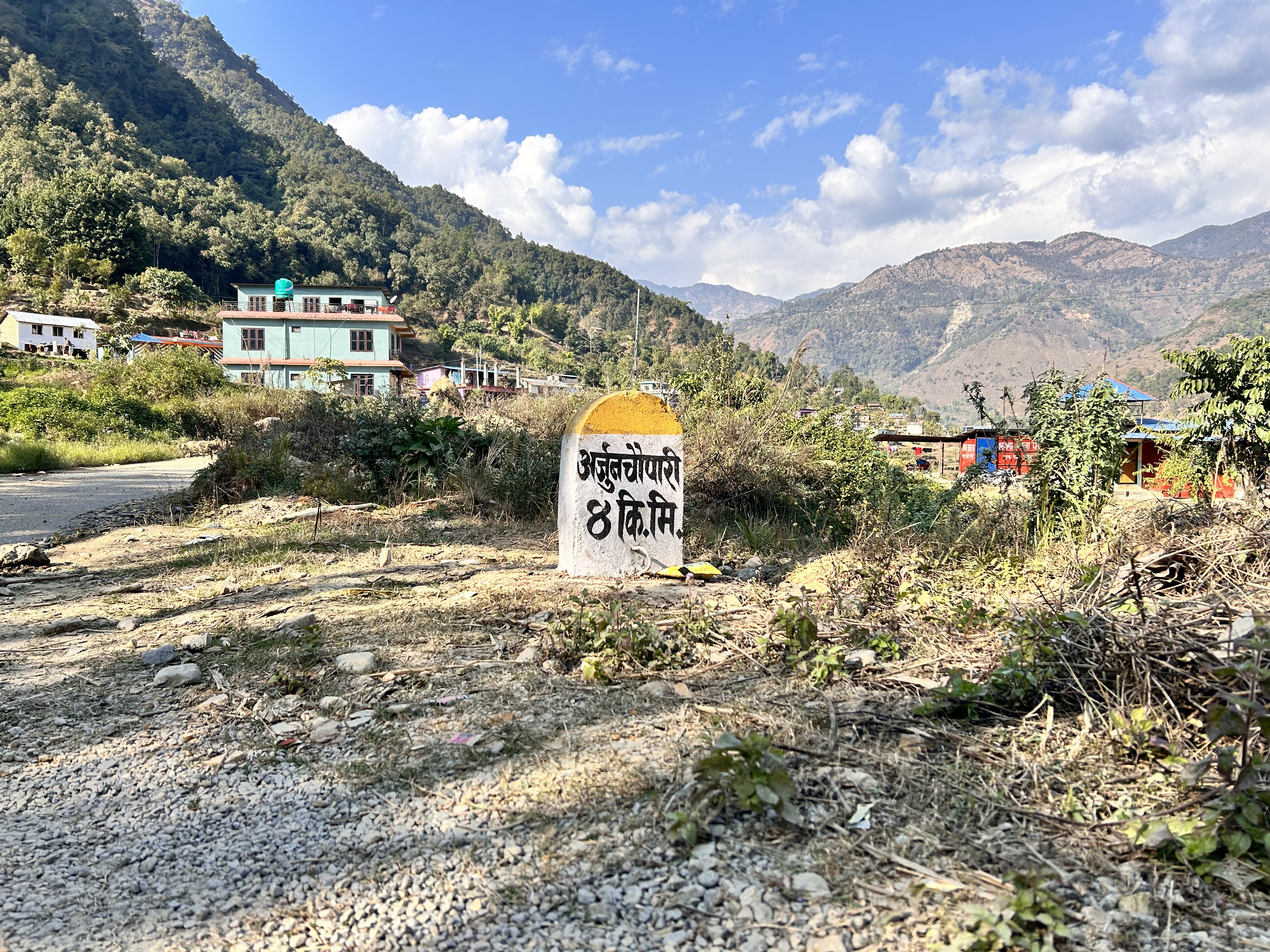 A road sign indicating kilometers on a newly constructed road: Arjunchoupari - 4km ahead.