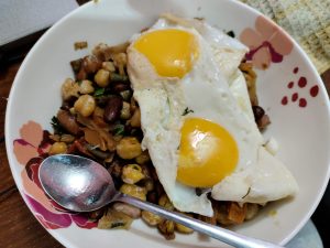 A bowl of food with a fried egg on top.