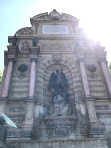 The Fontaine Saint-Michel in Paris, France with the sun in the upper right corner.