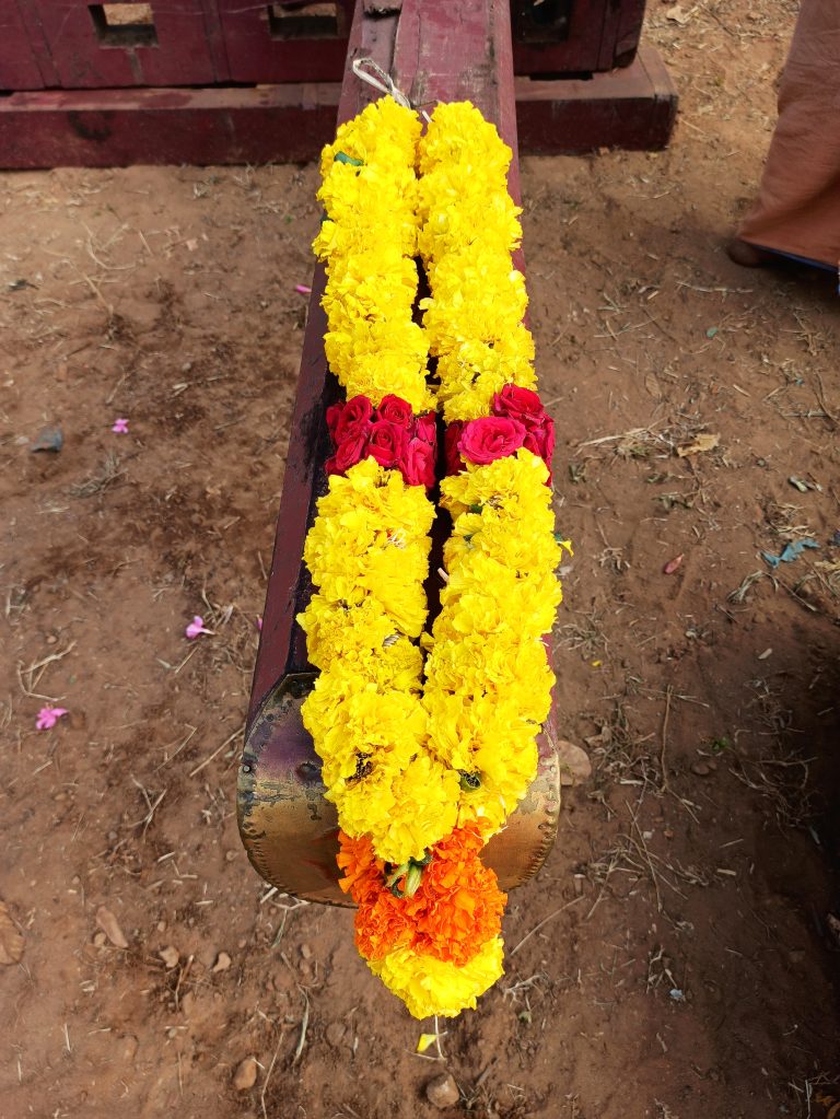 A garland made of yellow-orange marigold ( Jamanthi ) flowers and red roses.