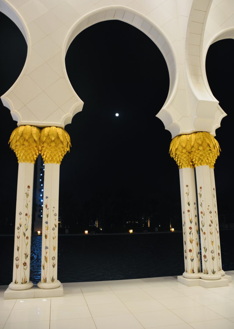 Moon between two pillars. A night view from Grand Mosque, Abu Dhabi, United Arab Emirates.