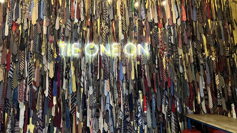 “Tie One On” mural inside Monday Night Brewing in Atlanta, Georgia, consisting of a wall of neck ties with a neon sign that says “Tie One On”