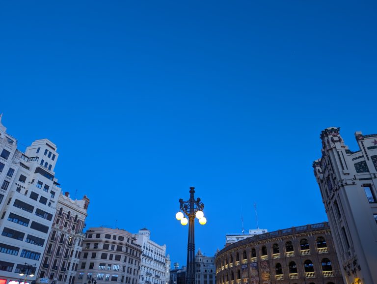 In Valencia, a clear scene unfolds with blue skies, buildings, and streetlights.