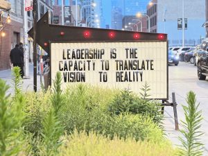 Sidewalk sign with the text "Leadership is the capacity to translate vision to reality"