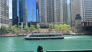 Lila sightseeing tour boat on the Chicago River with The River Theater on the Riverwalk in the background