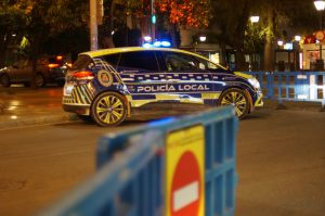 Night police control in Sevilla; a yellow and blue police car on a well-lit street at night in Sevilla