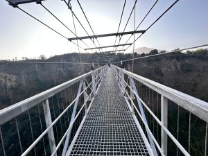 View larger photo: Looking down a suspension foot bridge over a deep canyon.