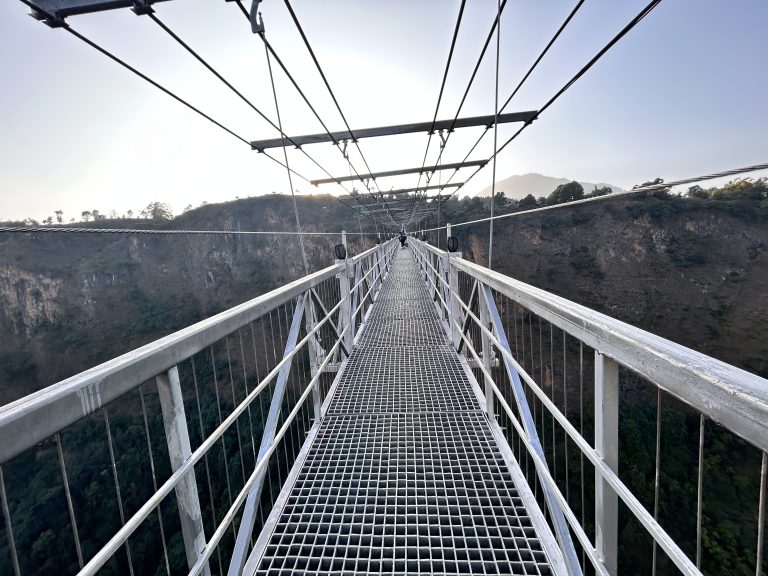 Looking down a suspension foot bridge over a deep canyon.