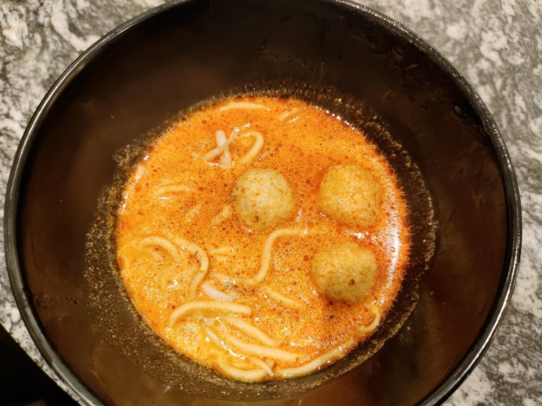 A bowl of soup with noodles and meatballs