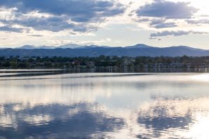 Denver's Sloan Lake with houses in the middle and the Rocky Mountains in the background