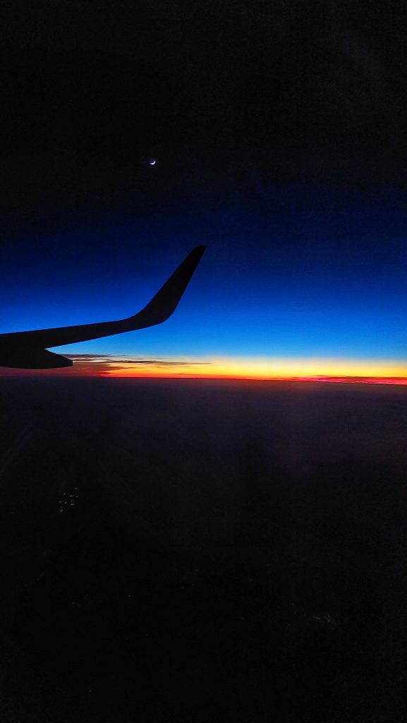 Sunset view from a flight with its wings and moon in the frame.
