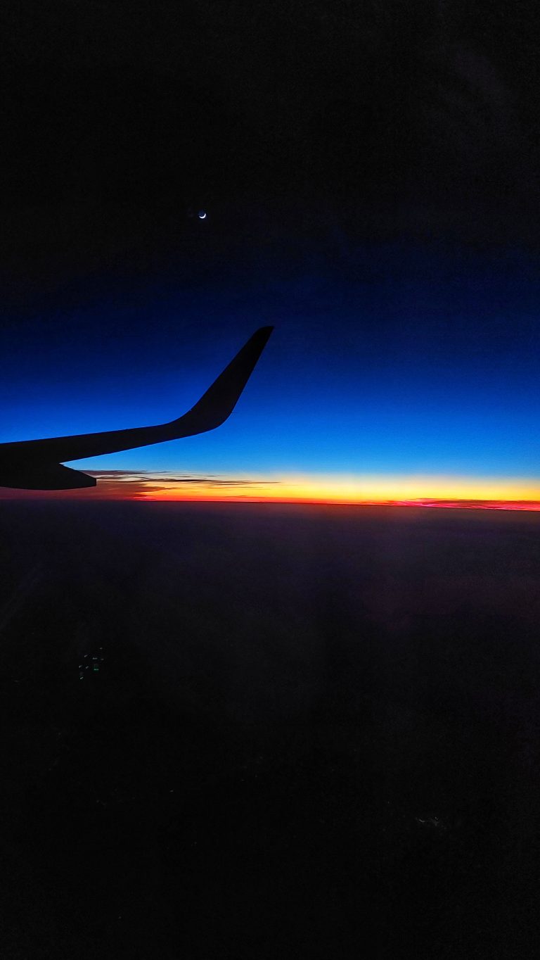 Sunset view from a flight with its wings and moon in the frame.