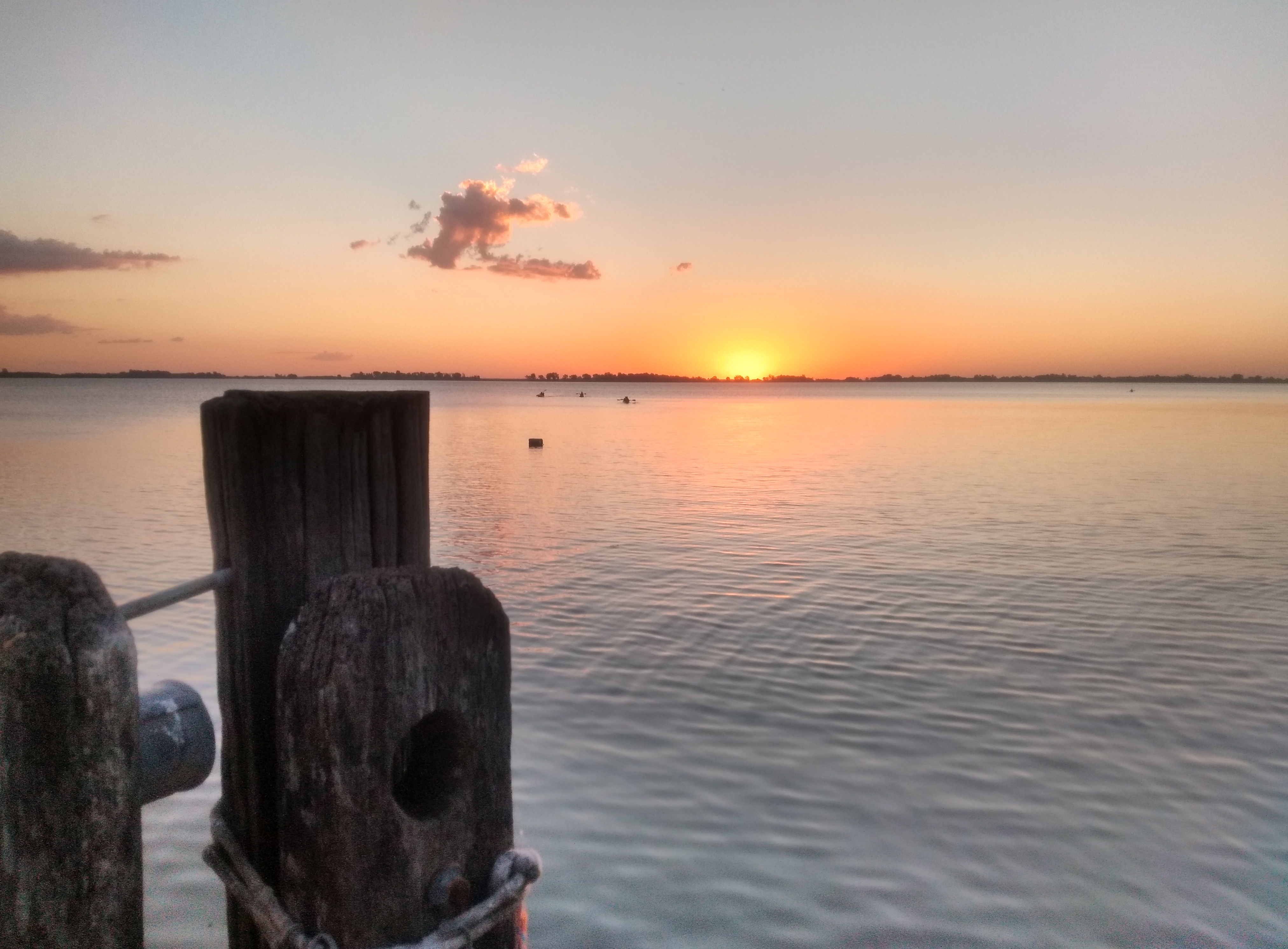 Sunset over a body of water and wooden posts in the foreground. Atardecer laguna Chascomús, Argentina