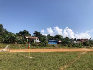 Goal post in on of the village n village houses on the background .