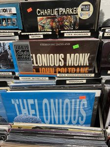 A close up of a rack in the jazz section of a record store. Some records by Thelonious Monk, John Coltrane, and Charlie Parker are visible. 