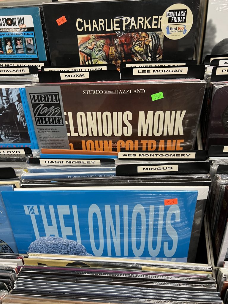 A close up of a rack in the jazz section of a record store. Some records by Thelonious Monk, John Coltrane, and Charlie Parker are visible.